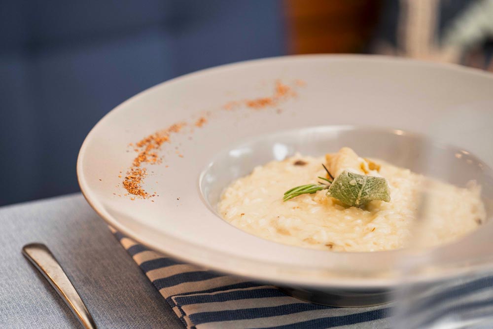 Risotto ai funghi porcini con riso carnaroli con funghi porcini trifolati, gocce di zola e polvere di cipolla